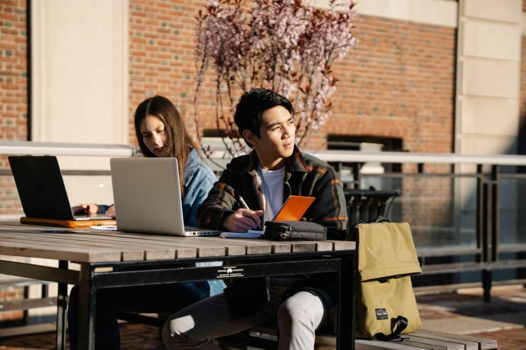 An image depicting a student studying with a car in the background, representing good student discounts. — car insurance…
