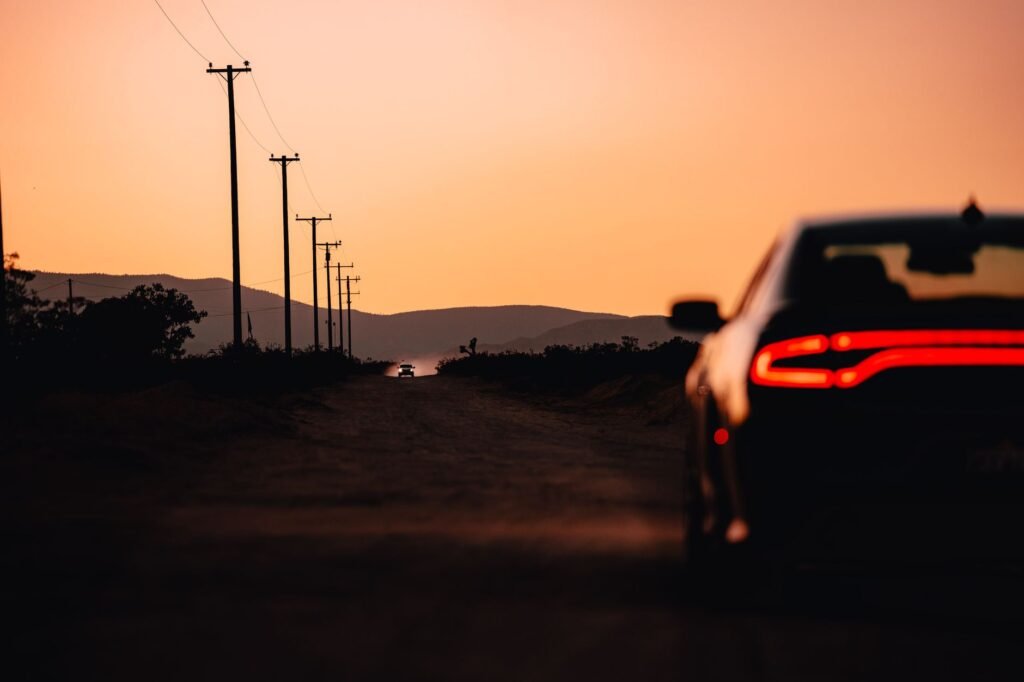An image of a car navigating a desert road during a sunset. — Nevada driving conditions car insurance